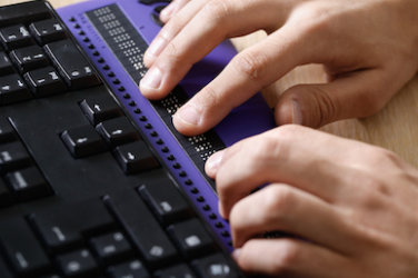 A pair of hands touches a braille display.