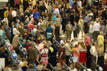crowded conference room, with people sitting or standing and talking to others