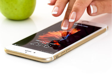 A finger touches the screen of an iPhone.