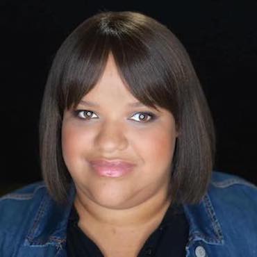 Nefertiti Matos headshot. She smiles softly. She has short brown straight hair with bangs, tanned skin, and full lips. 