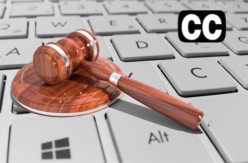 A gavel rests on a keyboard. On the upper right corner, the letters CC float