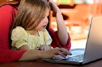 Girl and a woman look a laptop screen