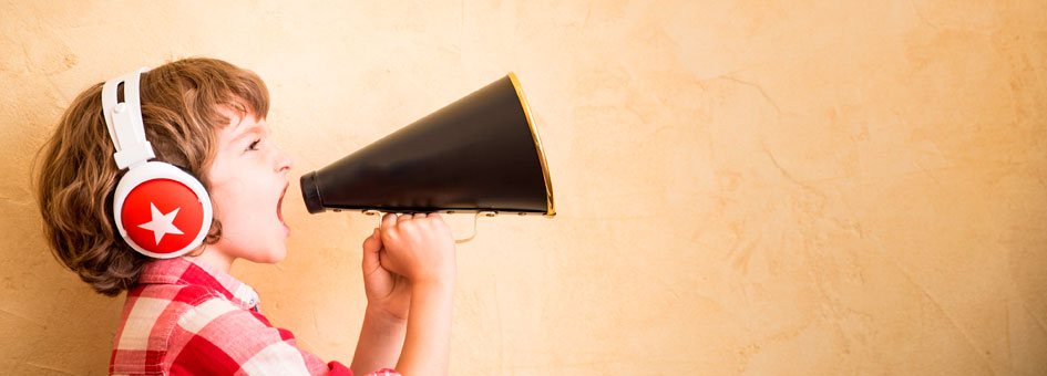 A boy wearing headphones shouts out using a megaphone