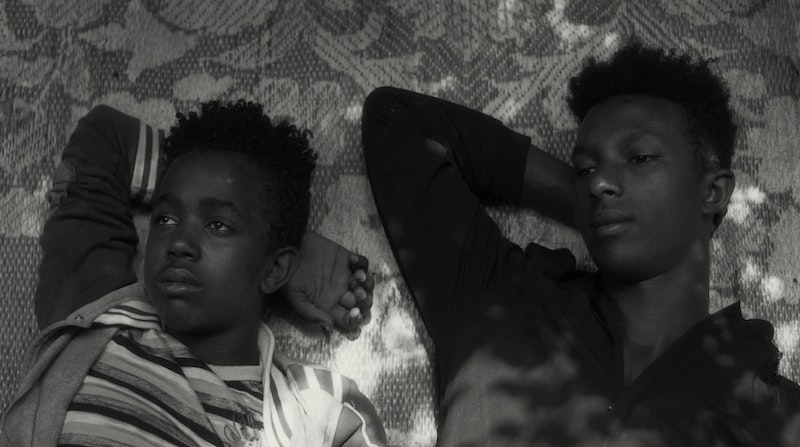 two young men lie in the ground looking at the sky