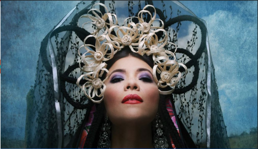 Face of Geo Meneses with a large black comb on her head and some flowers made with beige ribbons.