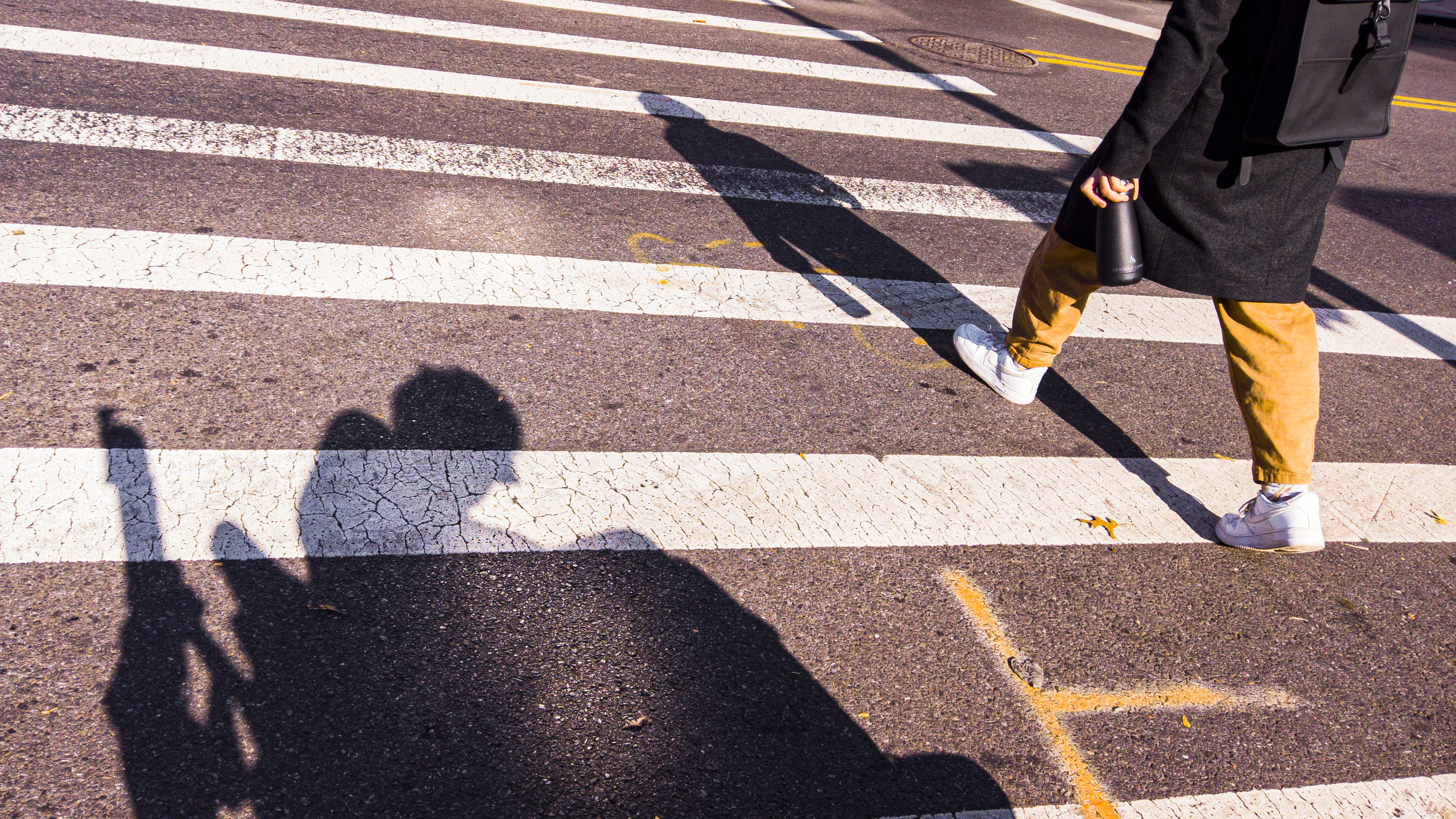 the shadow of a man on a wheelchair projects on a crosswalk