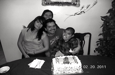 Myrna, her daugther, her husband and her son Norman in front of a cake.