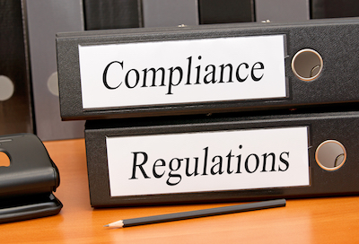 2 binders on a table, On their spines is written “Compliance” and “Regulation”