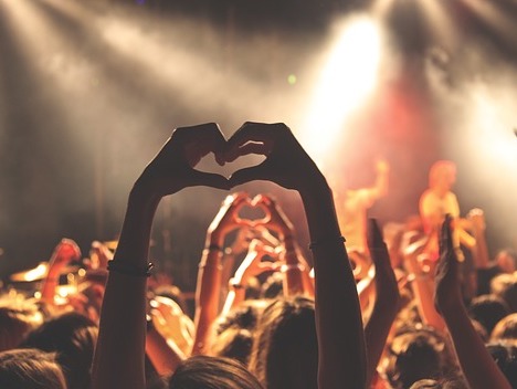 Concert audience. People raise their arms and forms a heart with their hands