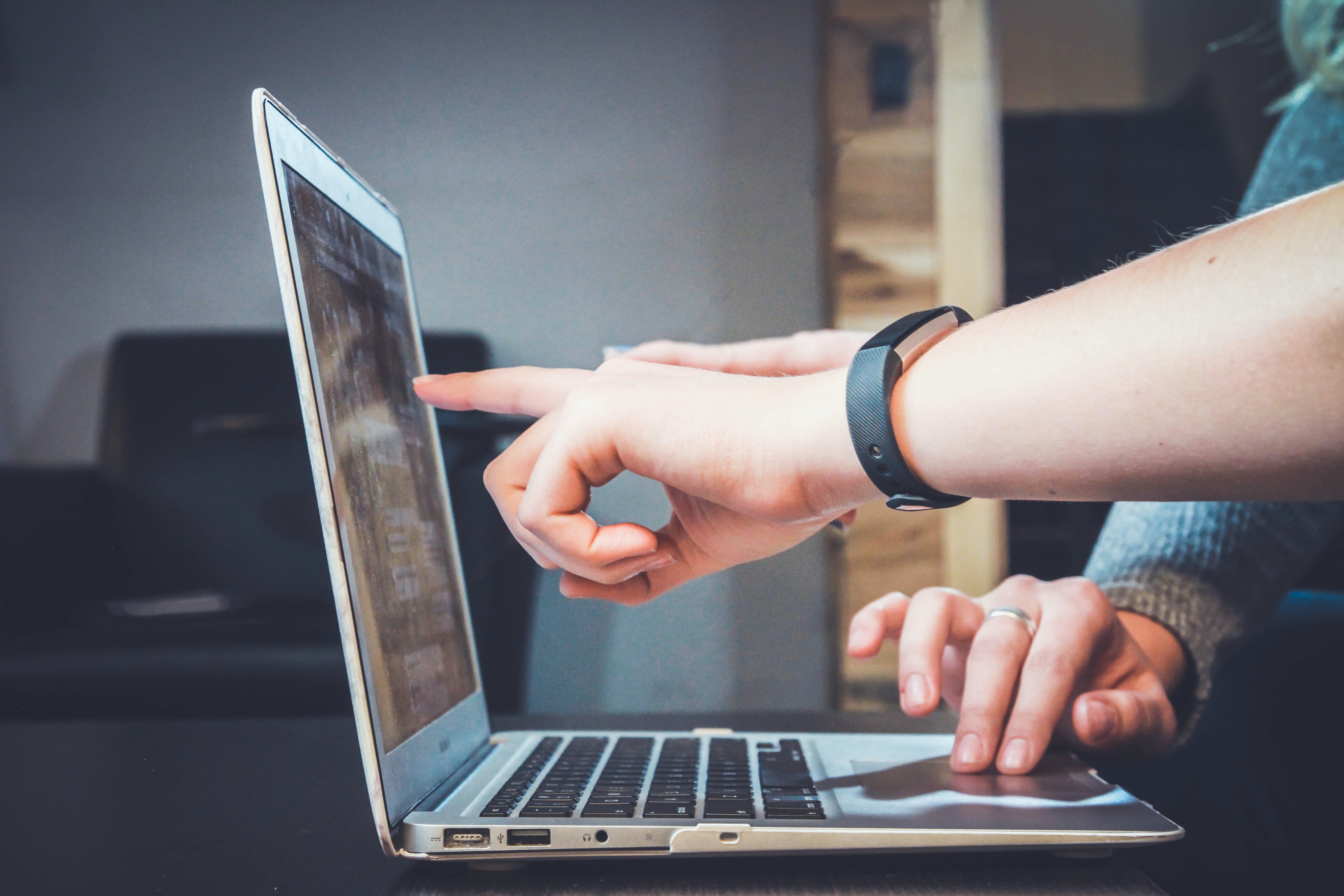Two hand pointing at the screen of a laptop